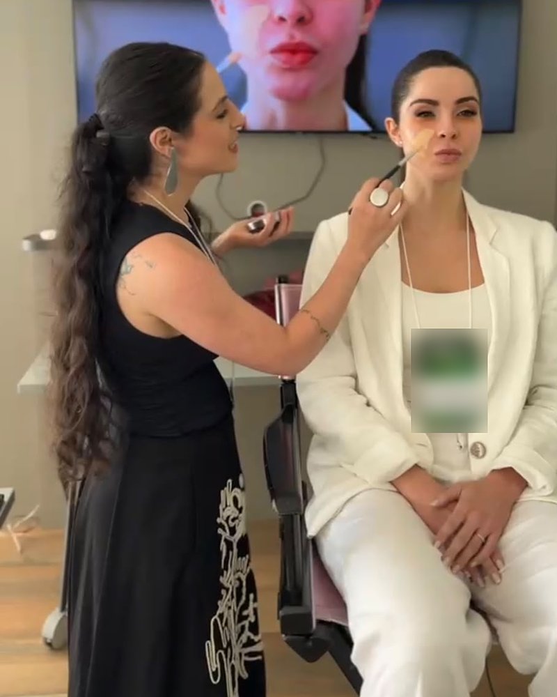 Salime Abdalla maquiando uma modelo enquanto uma câmera mostra o rosto dela na TV