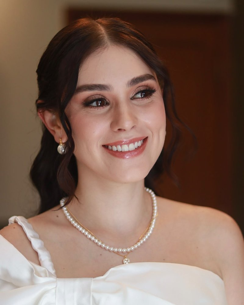 Noiva sorrindo, com colar de pérolas e maquiagem leve