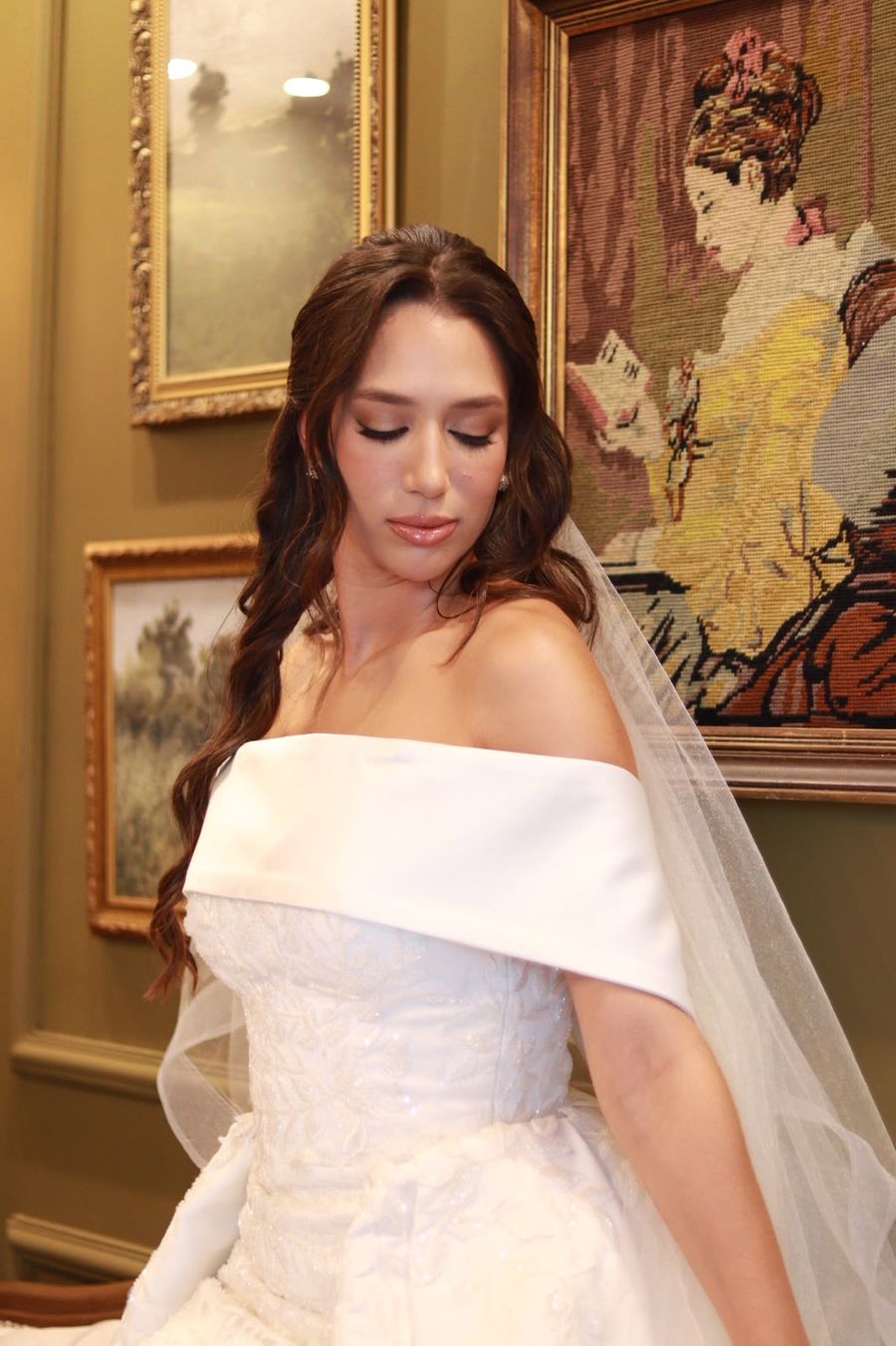 Noiva com vestido de ombro a ombro em sala com quadros