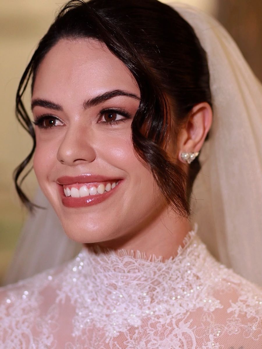 Noiva sorrindo com véu e vestido de renda
